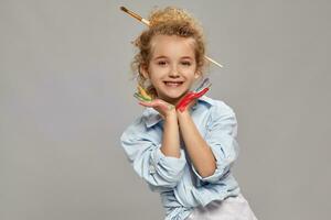 Beautiful little girl with a painted hands is posing on a gray background. photo