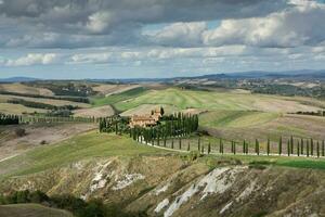 famoso toscana paisaje con curvo la carretera y ciprés, Italia, Europa. rural granja, ciprés árboles, verde campo, luz de sol y nube. foto