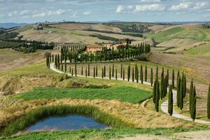 Famous Tuscany landscape with curved road and cypress, Italy, Europe. Rural farm, cypress trees, green field, sunlight and cloud. photo