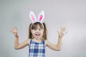 Cheerful little girl with bunny ears on a gray background. photo