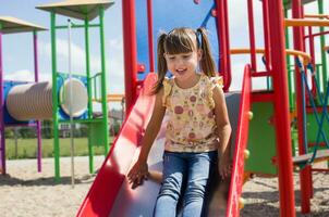 Little happy girl playing on the playground. Outdoor fun photo