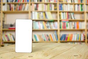 Phone on a wooden table in the library. Mockup. Learning concept. Copy space photo