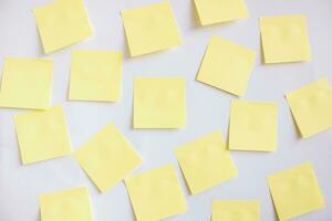 Many yellow papers for notes on a white wall. photo