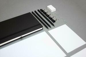 computadora portátil, lápices, papelería y plantillas de diferente formas en un gris antecedentes foto