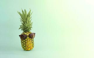 Ripe pineapple in sunglasses on a colored background. Vacation concept. photo