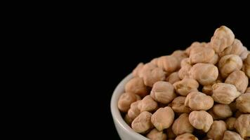 Chickpeas vegetables gyrating on a bowl in black background justified at right video