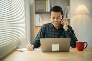 Freelance business man calling on mobile smartphone while working with laptop on table, businessman mobile phone to calling with customers or shopping online. Smart phone conversation conferrence. photo
