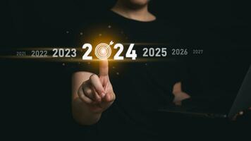 Trends 2024 year concept. Woman hold laptop and point finger touching virtual sequence count down years 2024 wording for marketing monitor business planning in new year. Technology new year concept. photo