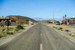 an empty road in the desert with mountains in the background photo