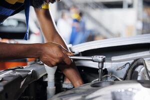 Serviceman in car service using professional mechanical tool to repair broken engine. Seasoned worker in garage repairs client automobile, ensuring optimal automotive performance, close up photo