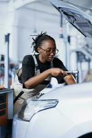 Repair shop technician expertly examines car motor using advanced mechanical tools, ensuring errorless automotive performance. Proactive worker in garage workplace conducts routine vehicle checkup photo