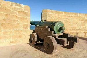 a cannon on a stone wall near the ocean photo