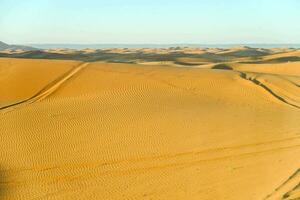 a desert with sand dunes and tracks in the distance photo