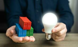 Shipping containers and an idea light bulb in hands. High-tech goods and products. Added value. Innovation and technology. Smart containers, equipped with cutting-edge sensors and tracking systems photo