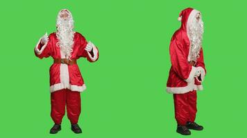 Father christmas with white beard and suit posing over full body greenscreen background, saint nick traditional embodiment. Young man acting like santa claus character with costume. photo