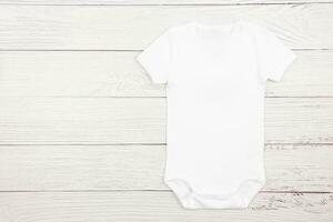 White baby girl or boy bodysuit mockup flat lay on wooden background. Design onesie template, print presentation mock up. Top view. photo