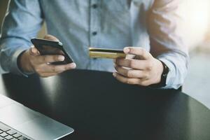 en línea compras y Internet pagos, asiático hombre son utilizando su crédito tarjeta y móvil teléfono a tienda en línea o conducta Diligencias en el digital mundo. foto