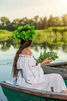 el ninfa con largo oscuro pelo en un blanco Clásico vestir sentado en un barco en el medio de el río. foto