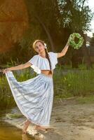 Young beautiful caucasian woman standing at the bank of river. Traditional countryside picture with girl at foreground and copy space. photo