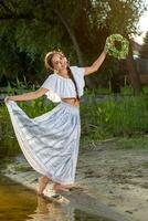 Young beautiful caucasian woman standing at the bank of river. Traditional countryside picture with girl at foreground and copy space. photo