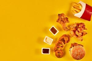 Top view hamburger, french fries and fried chicken on yellow background. Copy space for your text. photo