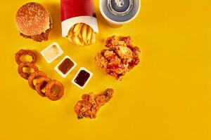 Top view hamburger, french fries and fried chicken on yellow background. Copy space for your text. photo