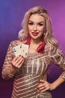 Blonde woman with a perfect hairstyle and bright make-up is posing with playing cards in her hands. Casino, poker. photo