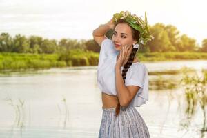 Young beautiful caucasian woman standing at the bank of river. Traditional countryside picture with girl at foreground and copy space. photo