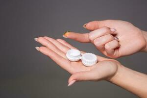 Contact eye lens. Close-up of woman hands holding white eyelense container. photo