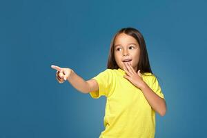 Cute girl shows finger on blue background photo