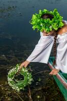 Young sexy woman on boat at sunset. The girl has a flower wreath on her head, relaxing and sailing on river. Fantasy art photography. photo