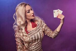 rubia mujer con un Perfecto peinado y brillante maquillaje es posando con jugando tarjetas en su manos. casino, póker. foto