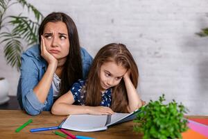 madre convirtiéndose frustrado con hija mientras que haciendo deberes sentado a el mesa a hogar en aprendizaje dificultades tarea. foto