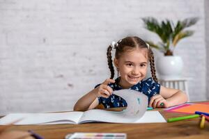 Inspired little girl at the table draw with crayons or do home work photo