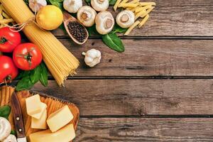 Ingredients for spaghetti with basil, tomatoes, cheese on wooden background, top view, place for text photo