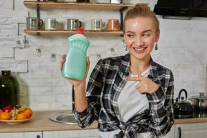 Housekeeper woman holding bottle with cleaner liquid. Bottle copy space photo