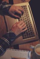 Young man drinking coffee in cafe and using laptop. Man's hands photo