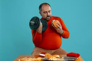 Close-up portrait of a middle-aged man with beard, dressed in a red turtleneck, posing with burgers and french fries. Blue background. Fast food. photo