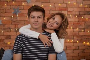 Relation emotions. Young man embracing attractive brunette wife indoor close up photo