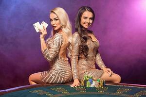 hermosa muchachas con un Perfecto peinados y brillante maquillaje son posando en pie a un juego mesa. casino, póker. foto