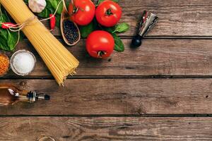Pasta and ingredients on wooden background with copy space. Top view. Vegetarian food, healthy or cooking concept. photo