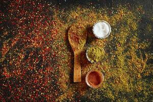 Assorted spices on dark black background. Seasonings for food. Curry, paprika, pepper, cardamom, turmeric. Top view. photo