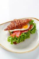 Sandwich from croissant with salted salmon, cucumber, fried egg and lettuce photo