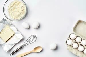 Preparation of the dough. Ingredients for the dough - flour, butter, eggs and various tools. On white background. Free space for text . Top view photo