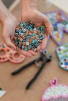 Workplace of the mosaic master women's hands holding mosaic details in the process of making a mosaic photo