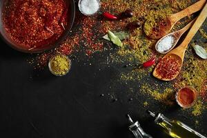 Assorted spices on dark black background. Seasonings for food. Curry, paprika, pepper, cardamom, turmeric. Top view. photo