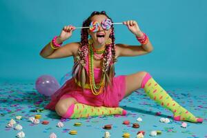 encantador niña con un multicolor trenzas peinado y brillante constituir, posando en estudio con chupete, aire globos y papel picado en contra un azul antecedentes. foto