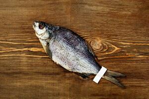 One whole salted sun-dried bream with label on tail on wooden background photo