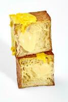 Sliced fluffy cube shaped croissant with vanilla custard, yellow glaze and chocolate chips photo