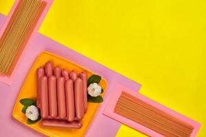 Sausages on a yellow and pink minimal background. Flat lay. Top view. photo